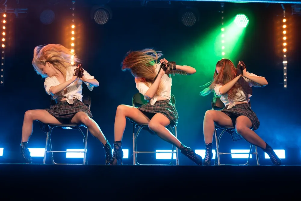 Två showartister genomför ett stilrent och kontrollerat stolnummer under en professionell scenproduktion.