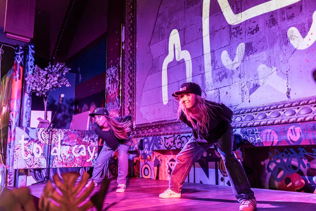 Showartister uppträder i ett koreograferat gruppnummer på scen under en energifylld men kontrollerad föreställning.