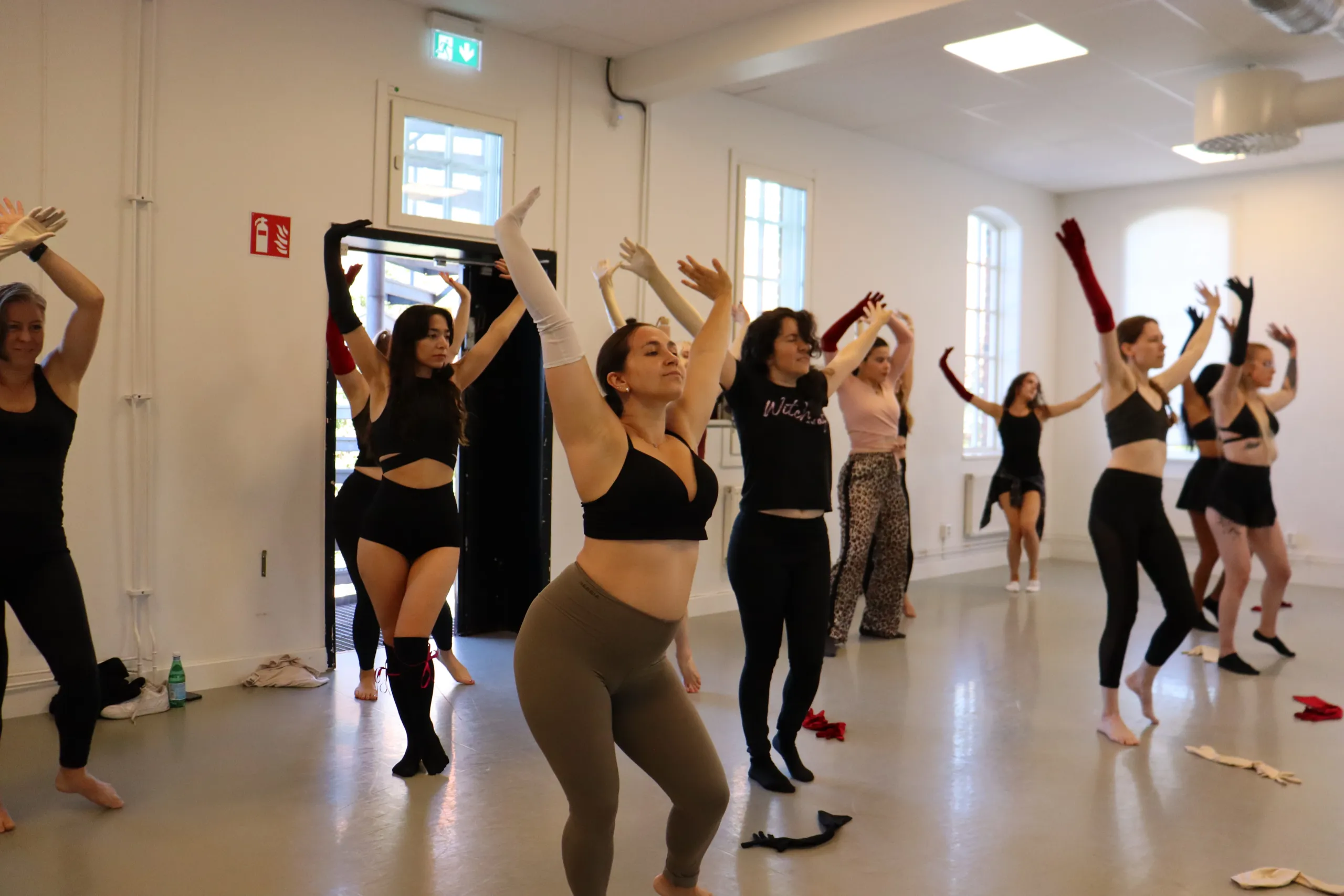 Deltagare på dansklass övar armrörelser och uttryck i gemensam koreografi.