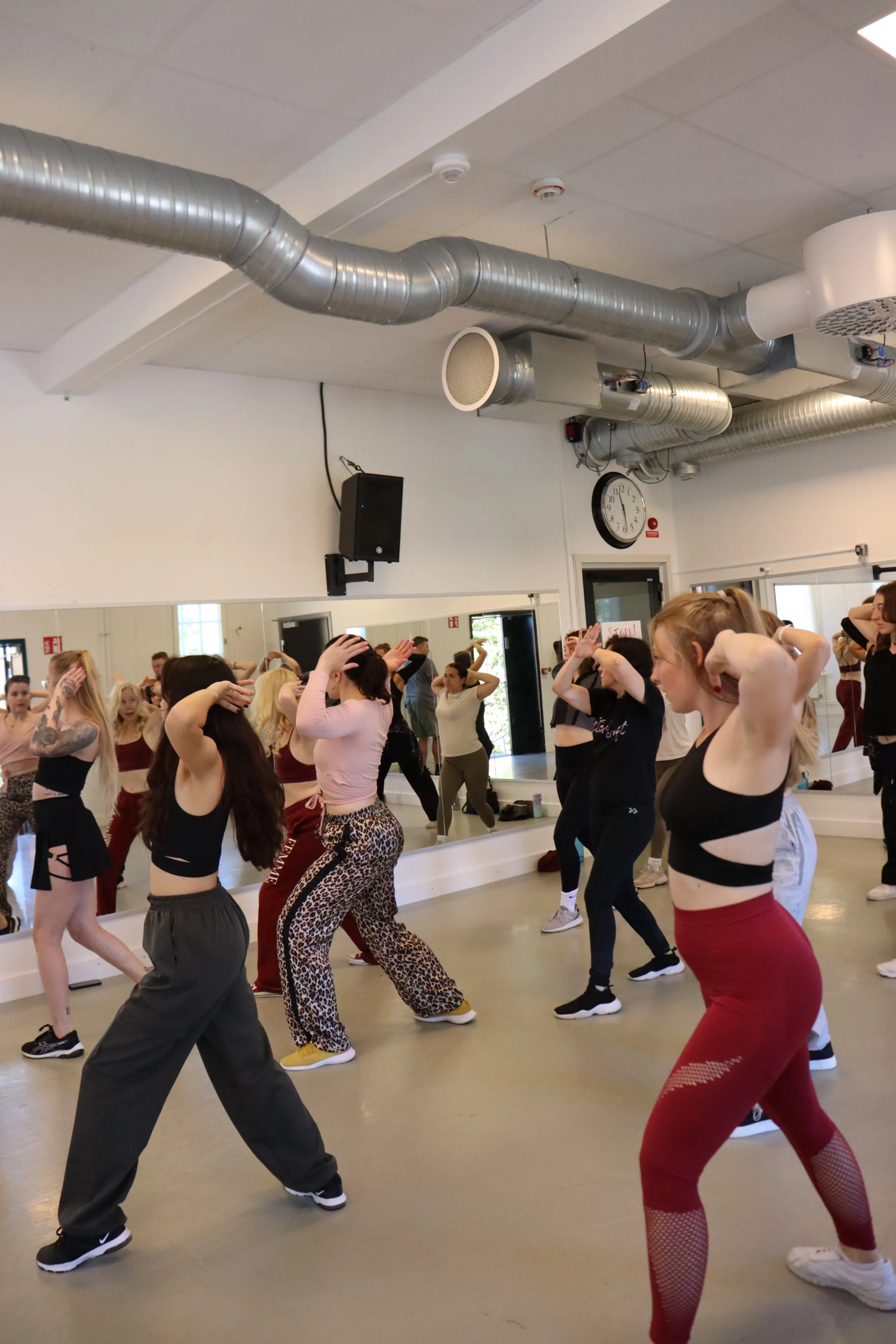 Gruppdansklass där deltagare tränar koreografi tillsammans i studio.
