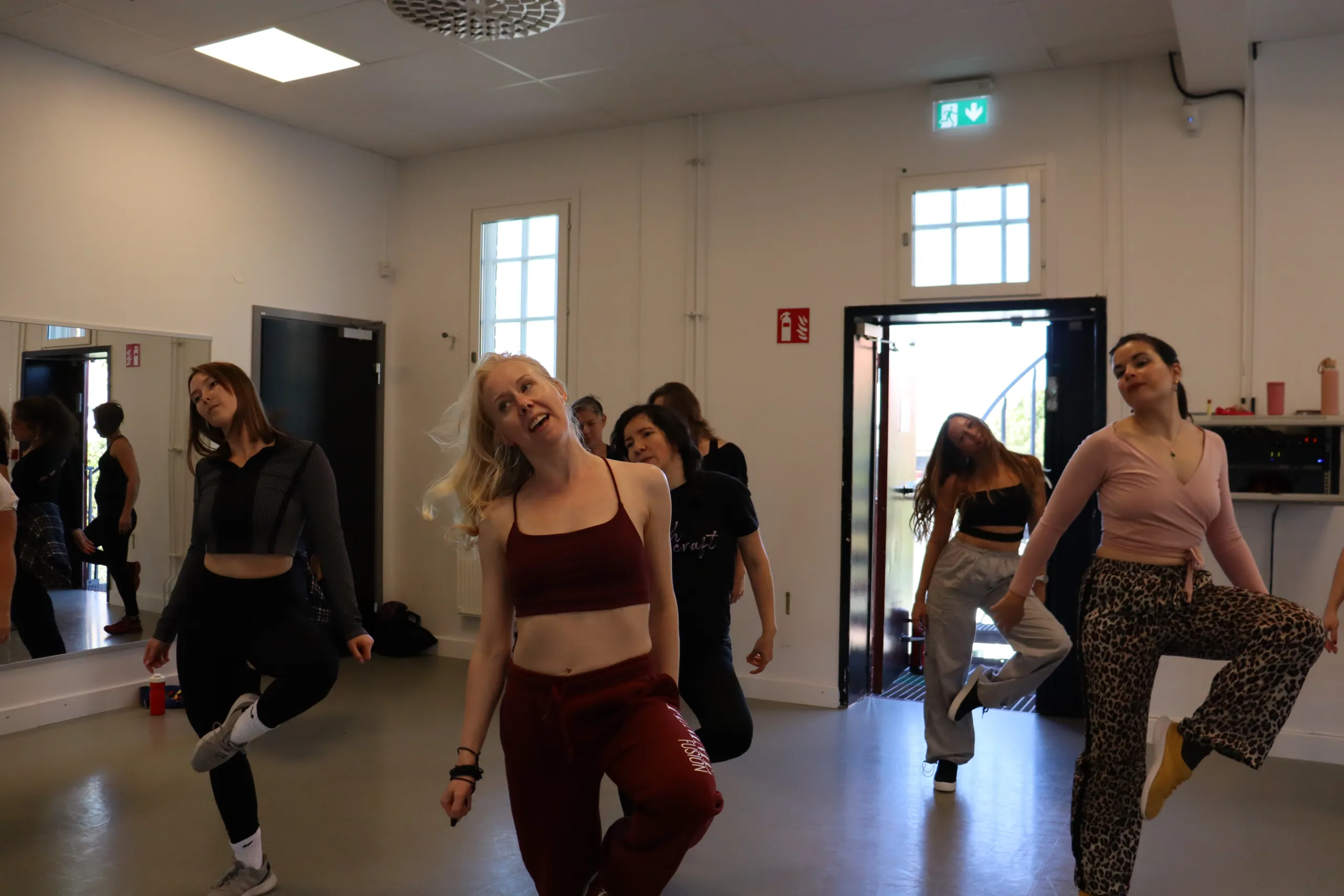 Dansklass i studio med gemensam uppvärmning och rörelseövningar.