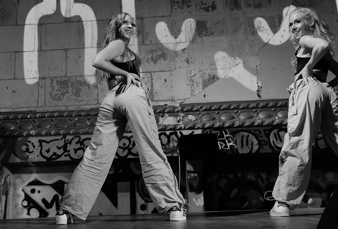 Två dansare poserar självsäkert på scen i feminine vibe-stil, med kraftfullt uttryck och urban känsla.
