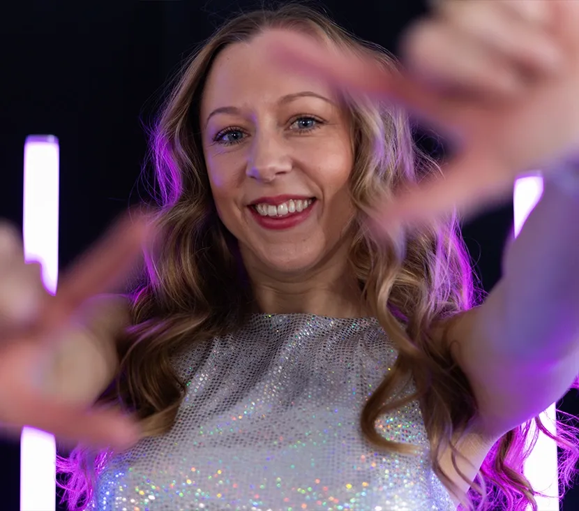 Närbild på dansare från Femme Fusion med glittrig scenkostym och lekfullt, inbjudande uttryck mot kameran.