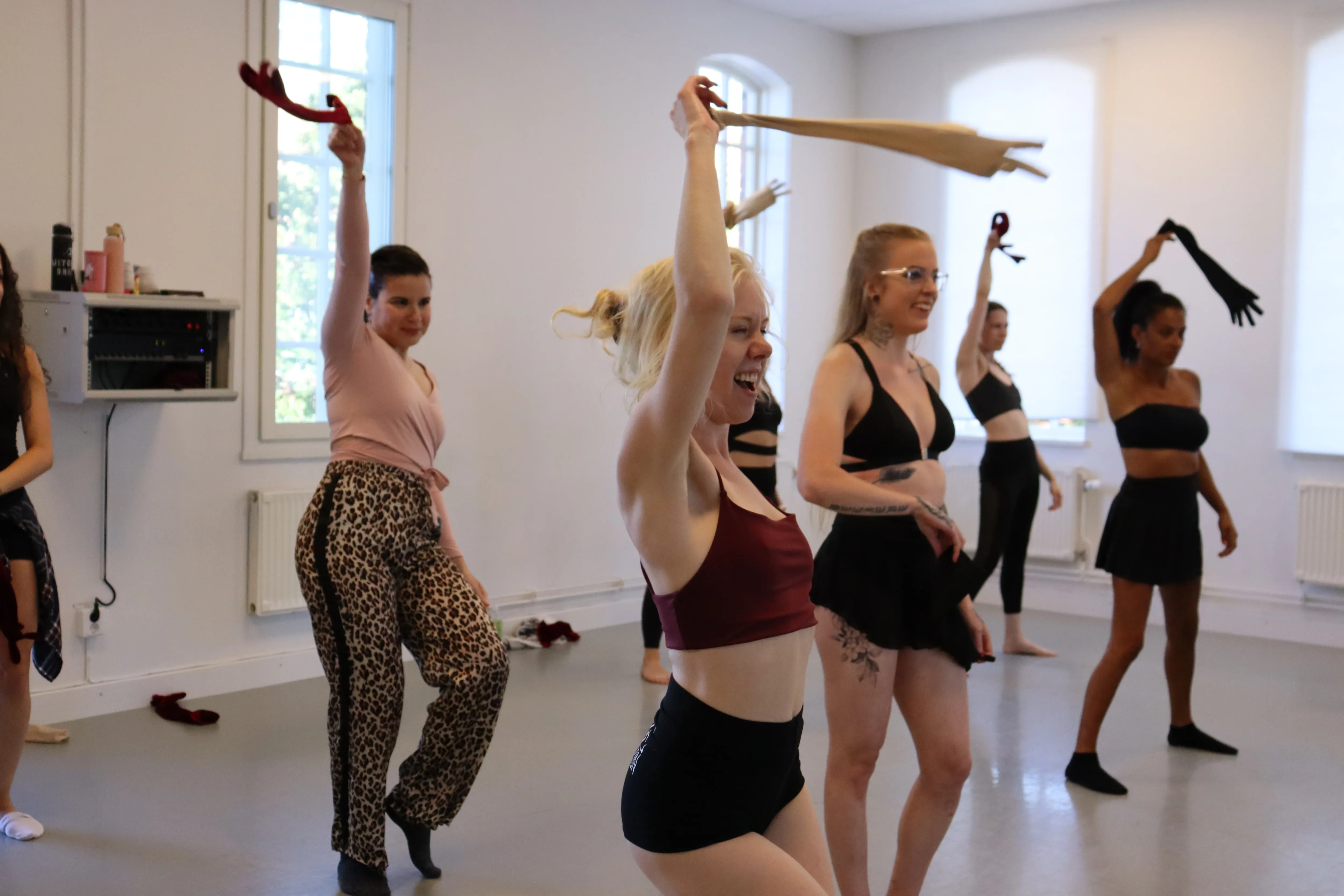 Deltagare dansar med handskar i en ljus studio under workshop i burlesque och feminine vibe.